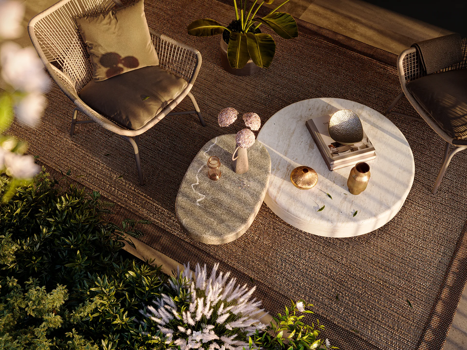 Fonte Laurentina: zona esterna con due sedie con cuscini grigi, due tavolini moderni con decorazioni e libri, e piante verdi con fiori bianchi.